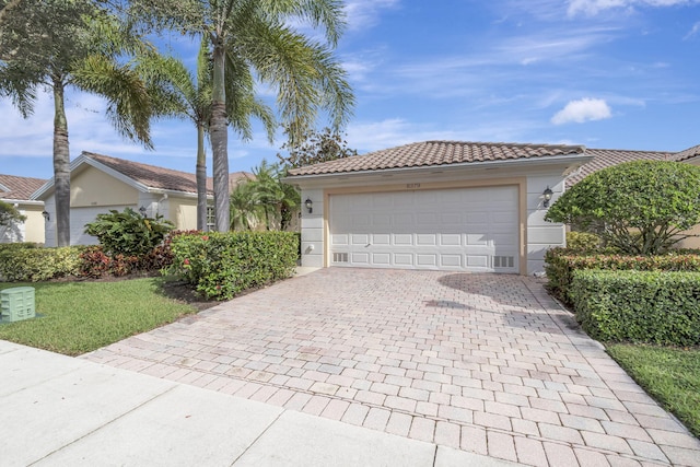 view of front of house with decorative driveway, a tiled roof, an attached garage, and stucco siding