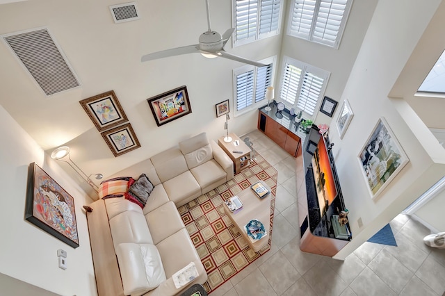 living room with a towering ceiling, light tile patterned floors, and ceiling fan