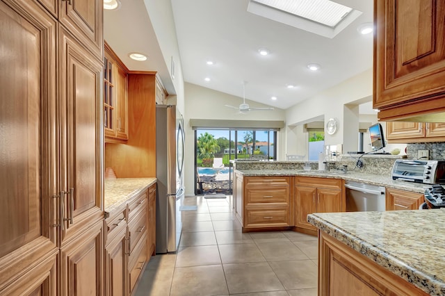 kitchen with light tile patterned flooring, sink, light stone counters, kitchen peninsula, and stainless steel appliances