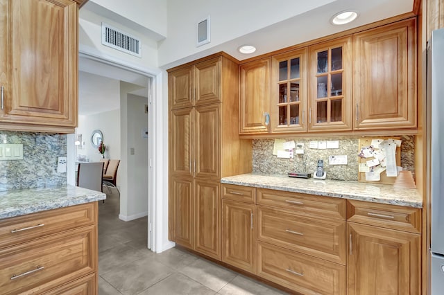 kitchen featuring backsplash, light stone countertops, and light tile patterned floors