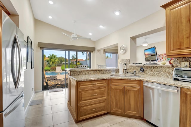 kitchen with dishwasher, sink, fridge, kitchen peninsula, and light stone countertops