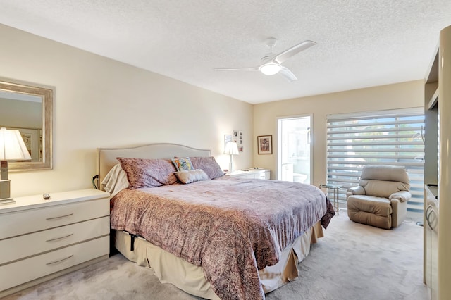 bedroom with ceiling fan, connected bathroom, light carpet, and a textured ceiling