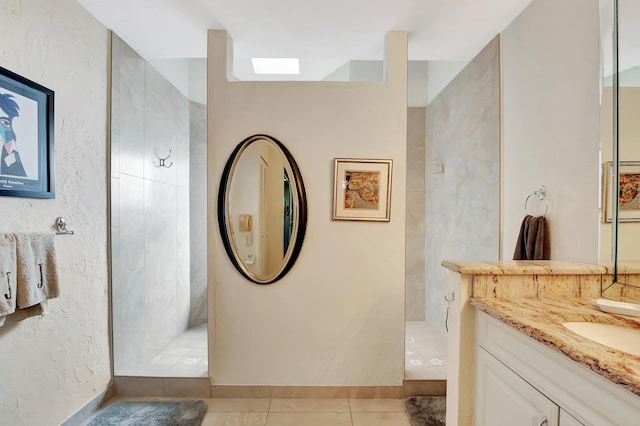 bathroom featuring tiled shower, vanity, and tile patterned flooring