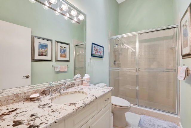 bathroom featuring vanity, a shower with shower door, tile patterned floors, and toilet