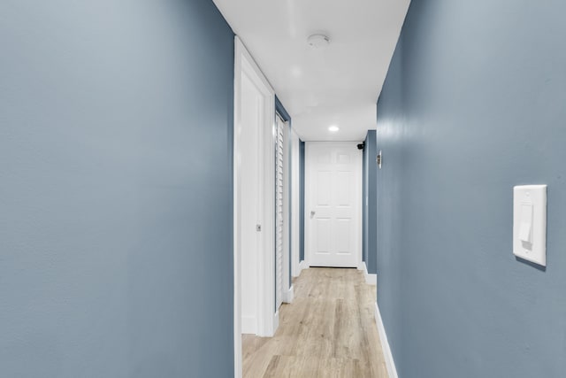 hall featuring light wood-type flooring and baseboards