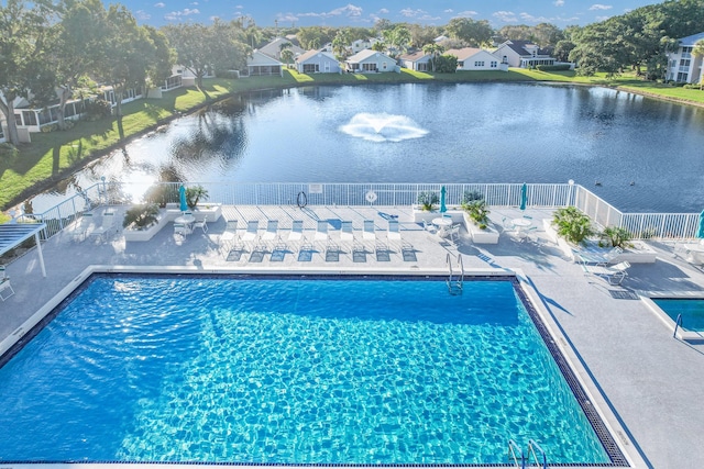 community pool featuring a water view, a patio area, a residential view, and fence