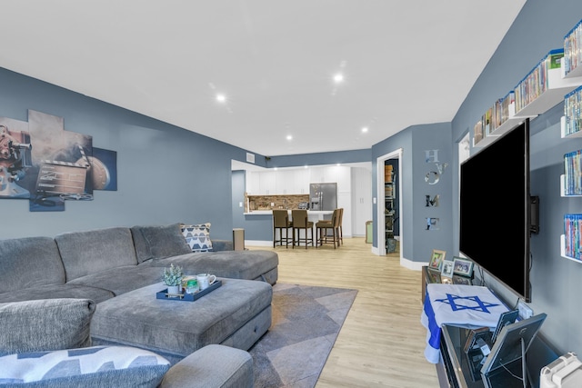 living area featuring light wood finished floors, baseboards, and recessed lighting