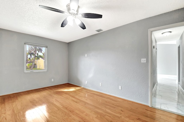 spare room with ceiling fan, a textured ceiling, and light hardwood / wood-style floors