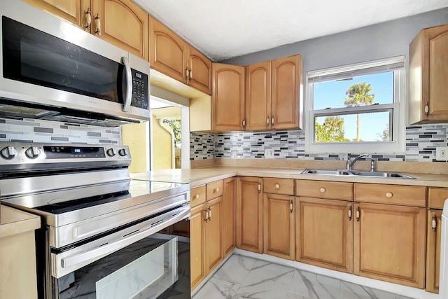 kitchen featuring a healthy amount of sunlight, stainless steel appliances, sink, and decorative backsplash