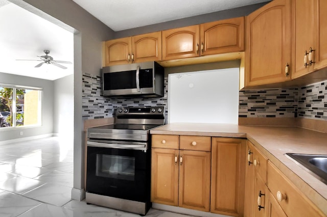 kitchen featuring appliances with stainless steel finishes, light brown cabinets, ceiling fan, and decorative backsplash