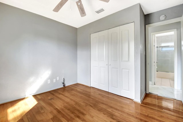 unfurnished bedroom featuring hardwood / wood-style floors, a closet, and ceiling fan