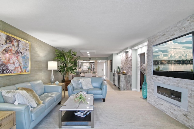 carpeted living room featuring a stone fireplace and a textured ceiling