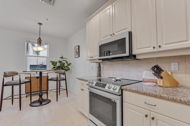 kitchen with backsplash, decorative light fixtures, white cabinets, and appliances with stainless steel finishes