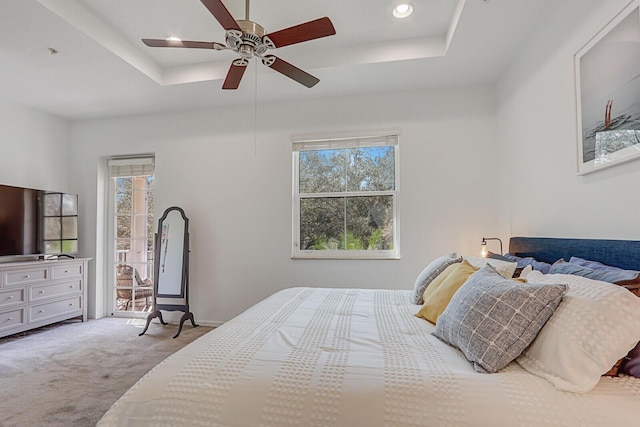 carpeted bedroom featuring ceiling fan, a raised ceiling, and access to outside