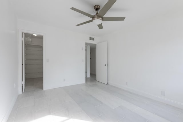 unfurnished bedroom featuring a walk in closet, ceiling fan, and a closet