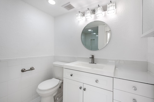 bathroom with vanity, tile walls, and toilet