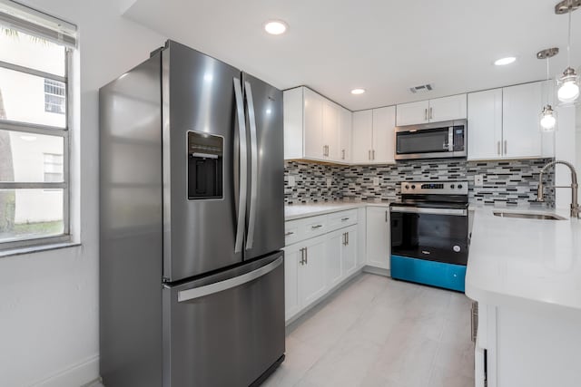 kitchen featuring a healthy amount of sunlight, sink, stainless steel appliances, and white cabinets