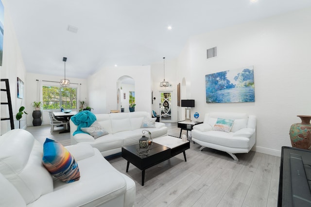 living room with light wood-type flooring and high vaulted ceiling