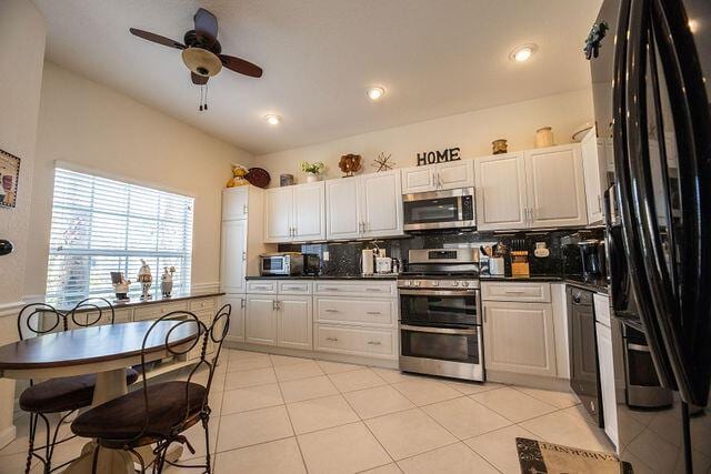 kitchen featuring stainless steel appliances, white cabinetry, light tile patterned flooring, and backsplash