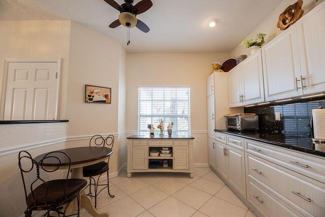 kitchen with tasteful backsplash, white cabinetry, light tile patterned floors, and ceiling fan