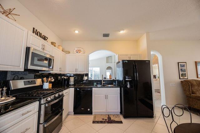 kitchen with white cabinets, light tile patterned floors, decorative backsplash, and black appliances