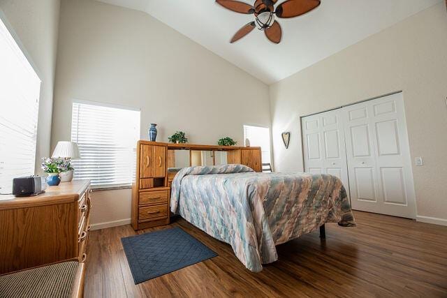 bedroom featuring dark hardwood / wood-style flooring, high vaulted ceiling, a closet, and ceiling fan