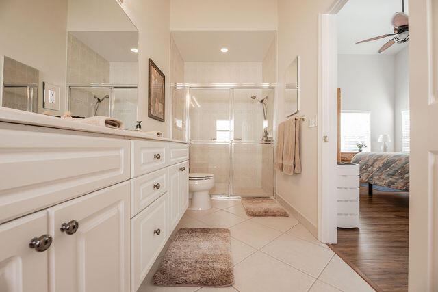 bathroom featuring tile patterned floors, toilet, an enclosed shower, vanity, and ceiling fan