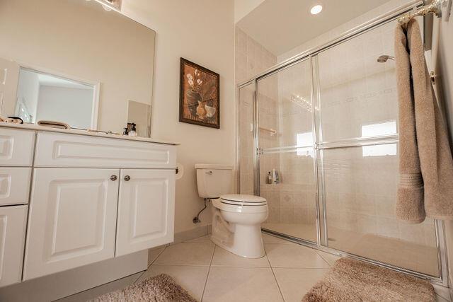 bathroom with tile patterned flooring, vanity, a shower with door, and toilet