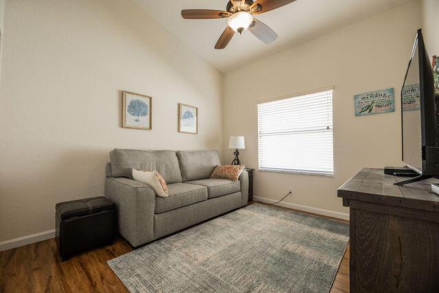 living room with lofted ceiling, dark hardwood / wood-style floors, and ceiling fan