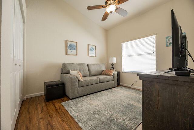 living room featuring vaulted ceiling, dark hardwood / wood-style floors, and ceiling fan