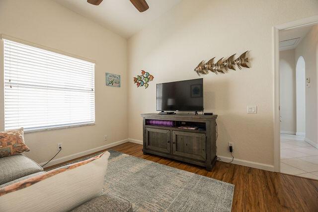 living room with dark hardwood / wood-style flooring, lofted ceiling, and ceiling fan