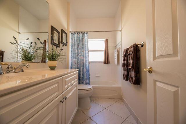 full bathroom featuring vanity, shower / tub combo with curtain, tile patterned floors, and toilet