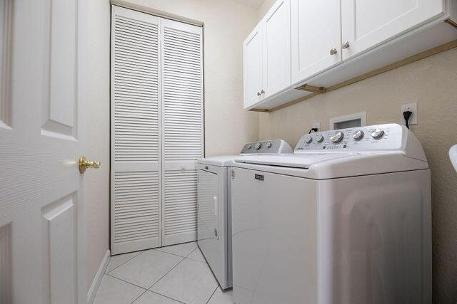 washroom featuring light tile patterned floors, washer and clothes dryer, and cabinets