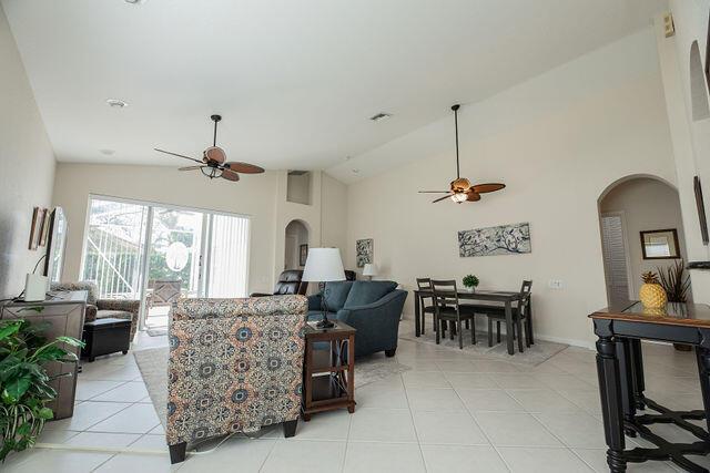 tiled living room with ceiling fan and high vaulted ceiling