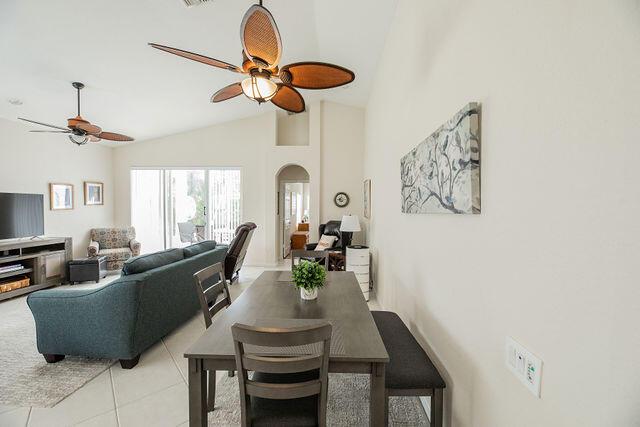 dining area with high vaulted ceiling, light tile patterned floors, and ceiling fan