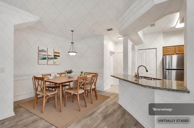 dining room with sink, tile walls, and light wood-type flooring