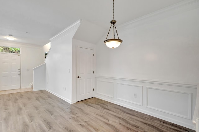 interior space with light wood-style floors, a decorative wall, ornamental molding, and wainscoting