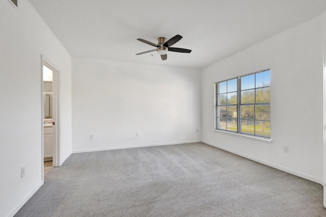 unfurnished room featuring light carpet, a ceiling fan, and baseboards