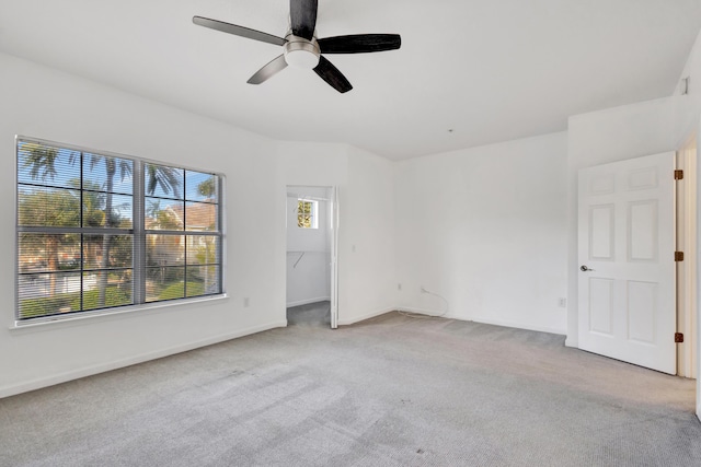unfurnished bedroom with carpet flooring, baseboards, a closet, ceiling fan, and a walk in closet