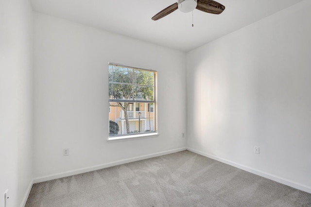 empty room featuring a ceiling fan, baseboards, and light carpet