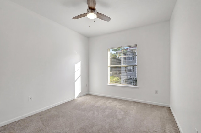 unfurnished room with a ceiling fan, baseboards, and light carpet
