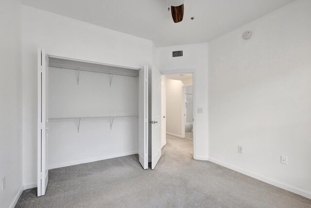 unfurnished bedroom featuring baseboards, visible vents, carpet, a ceiling fan, and a closet