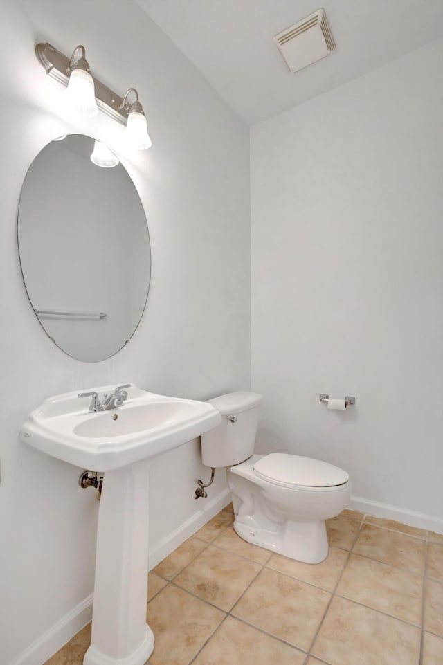half bath with toilet, tile patterned flooring, visible vents, and baseboards