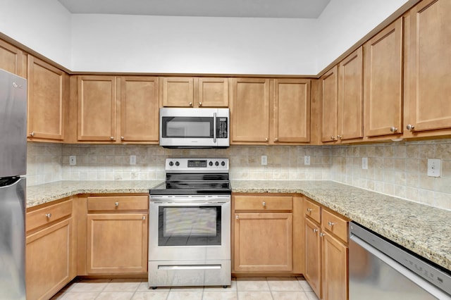 kitchen featuring tasteful backsplash, appliances with stainless steel finishes, light stone counters, and light tile patterned floors