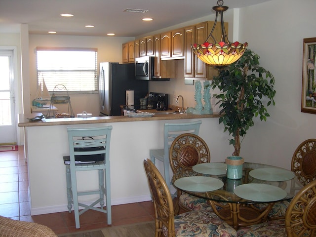 kitchen featuring sink, hanging light fixtures, appliances with stainless steel finishes, kitchen peninsula, and dark tile patterned floors