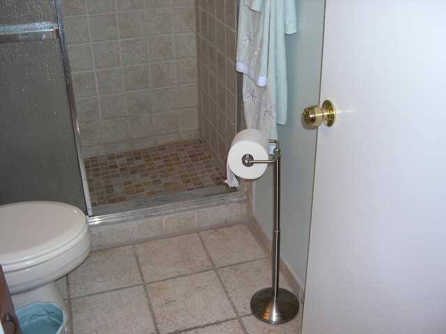 bathroom with tile patterned flooring, an enclosed shower, and toilet