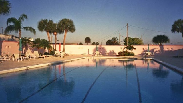 pool at dusk with a patio area