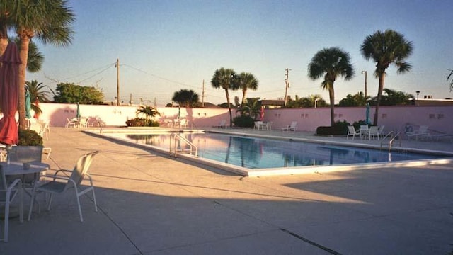 pool at dusk featuring a patio