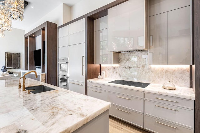 kitchen featuring sink, tasteful backsplash, black electric stovetop, light stone countertops, and stainless steel double oven