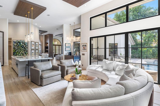 living room with sink, light hardwood / wood-style flooring, french doors, and a high ceiling